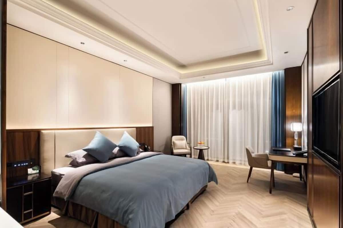 Ein modernes Hotelzimmer mit einem großen Bett, einem Schreibtisch und einem Fernseher.