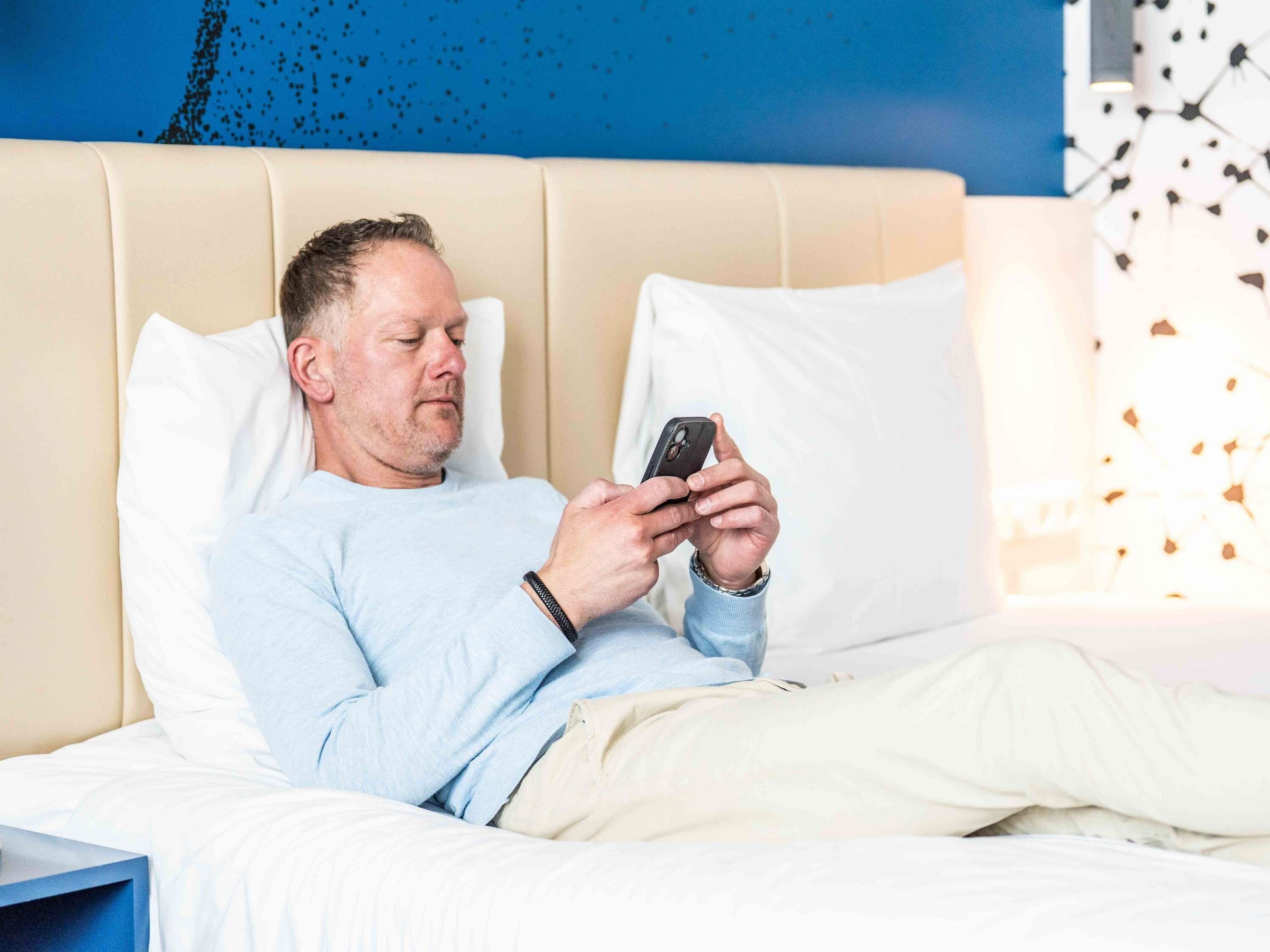 A person lying in bed using a smartphone.