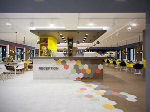 Zona de recepción con mostrador, asientos y un llamativo diseño de suelo hexagonal.