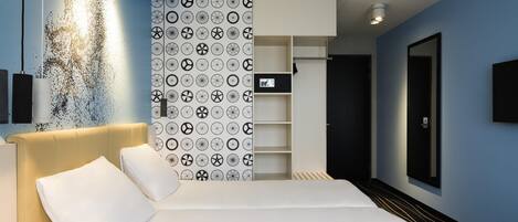 Una habitación de hotel moderna con una cama grande, un armario y un escritorio.