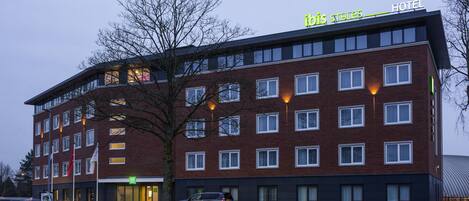 Un hotel de varios pisos con diseño moderno, que destaca un cartel grande con el nombre 'ibis Styles Hotel' en el techo.