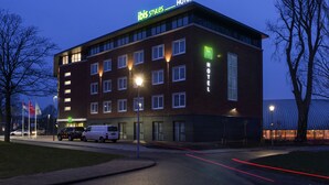 Un hôtel moderne, avec un toit plat, de nombreuses fenêtres et une enseigne indiquant qu’il s’agit d’un hôtel Ibis.