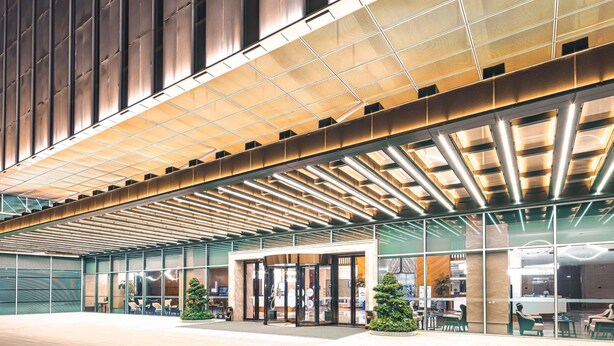 A modern building with a glass facade, a covered entrance area, and a seating area with chairs and tables. - ibis Styles Changsha International Exhibition Center (Changsha)