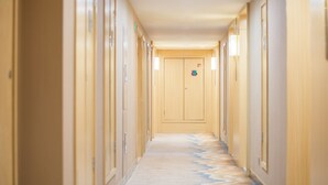 Passadís llarg i estret amb portes de fusta a ambdós costats, que condueix a una porta central amb un rètol.