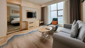 A hotel room with a bed, a TV mounted on a wooden cabinet, a seating area with a sofa and armchair, and a large window offering a city view. - ibis Styles Changsha International Exhibition Center (Changsha)