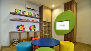 A children's play area with colorful stools, a round table, alphabet blocks, and a cartoon character. - Mercure Selangor Selayang (Batu Caves)