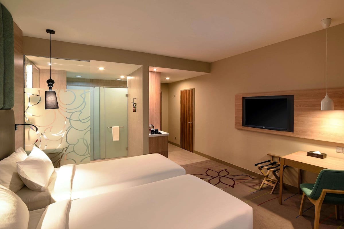 Una camera d'albergo con un letto, una scrivania, una TV e un bagno.