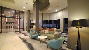 A modern lobby with a seating area, a KELUAR sign, and large windows.
