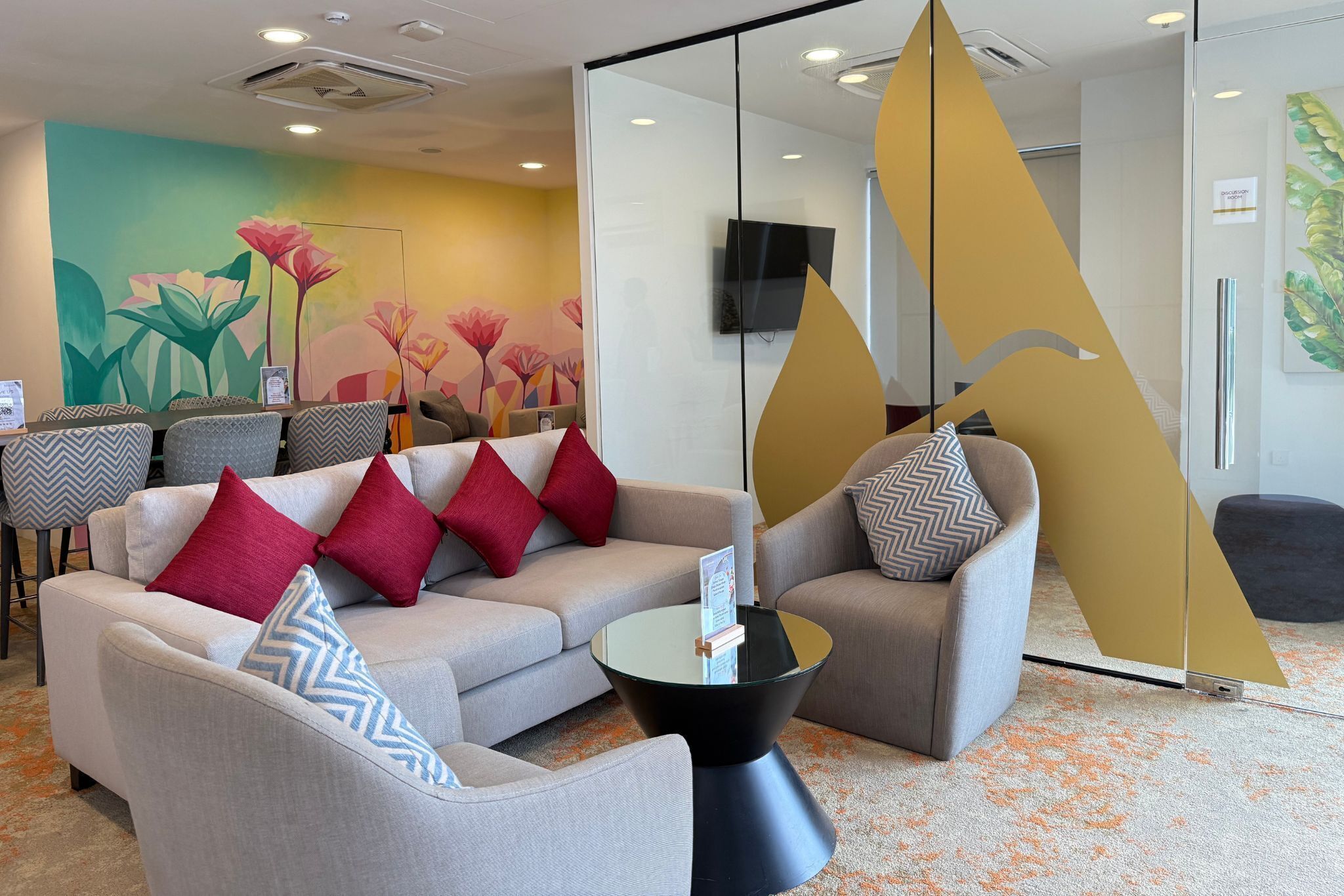 Eine moderne Lobby mit einer Couch, Sesseln, einem Couchtisch und einem Wandgemälde.