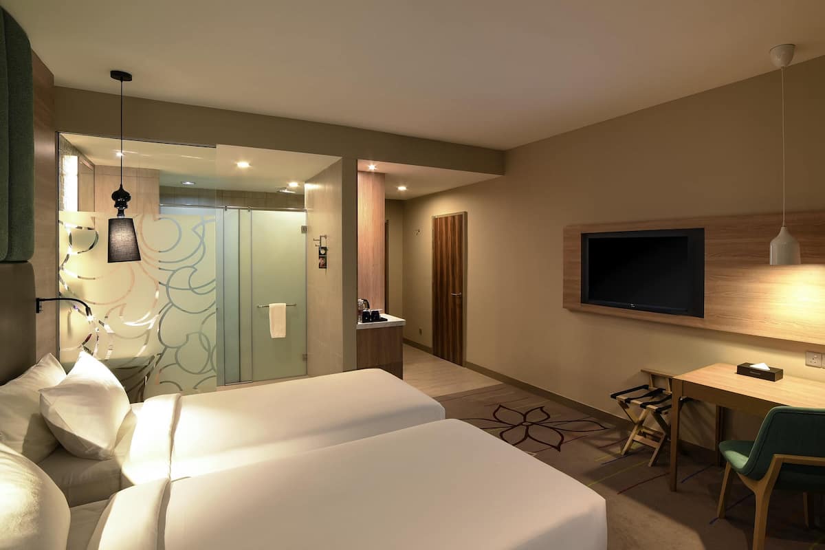 A hotel room with a bed, a desk, a TV, and a bathroom.