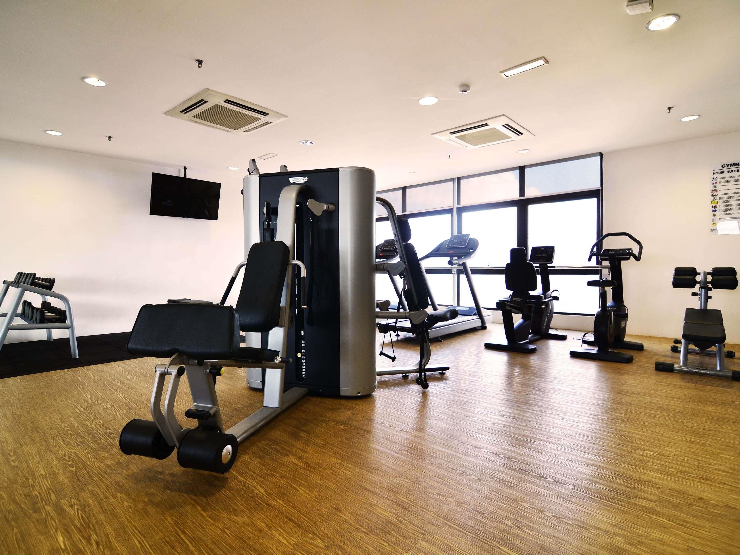 A gym with various exercise equipment, including a treadmill, elliptical, and weight machines.