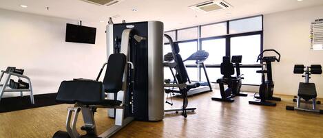 Un gimnasio con diversos equipos de ejercicio, como cintas de correr, elípticas y máquinas de pesas.