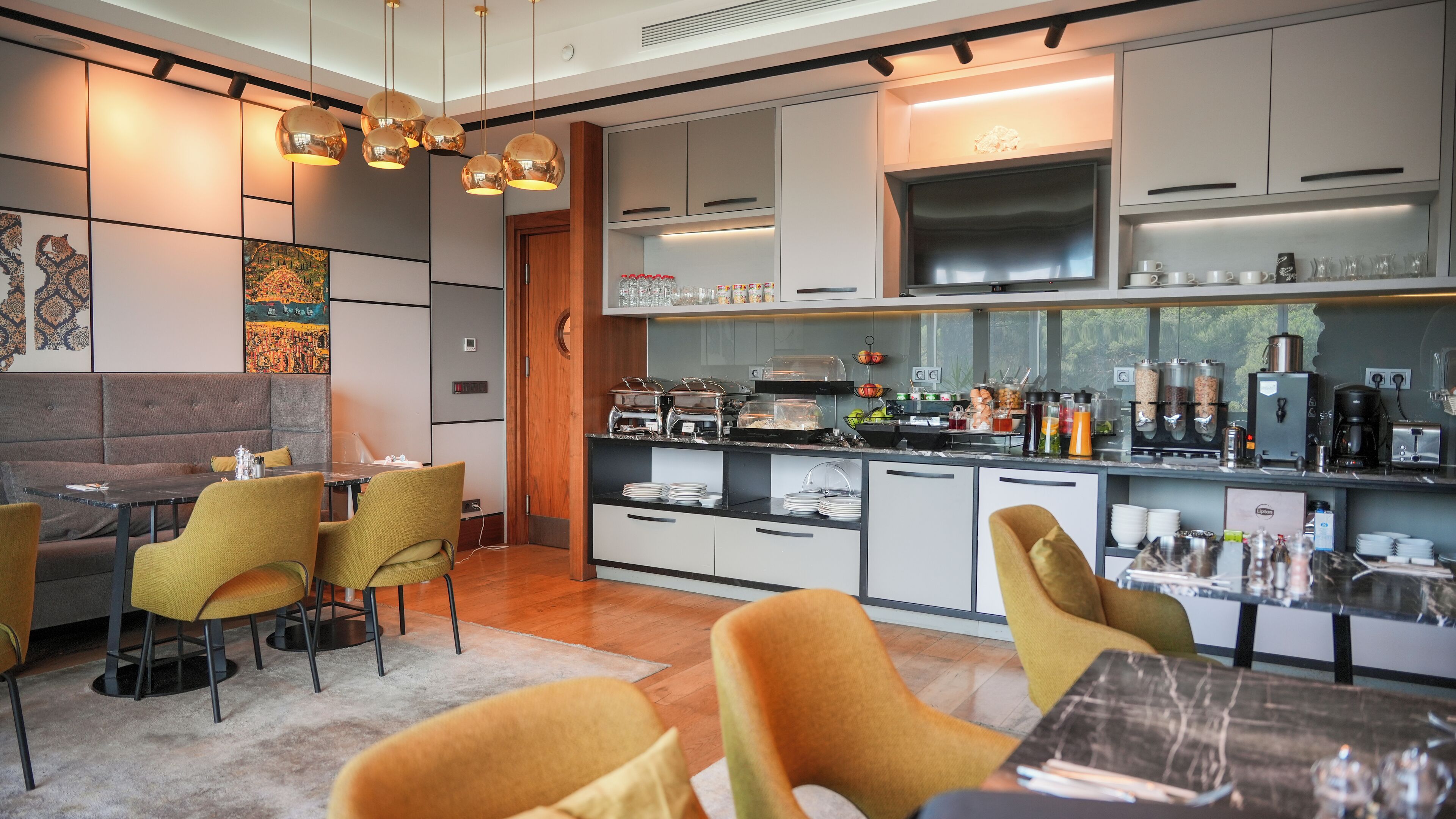Una cocina moderna con comedor, que incluye un sistema tipo bufé, un televisor de pantalla plana y una cafetera.