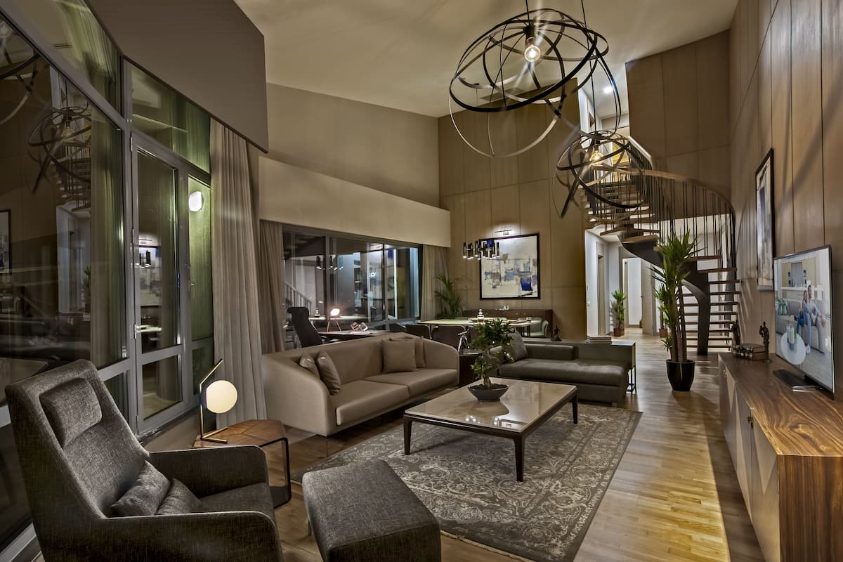 A spacious living area with a large sofa, a coffee table, and a modern chandelier.