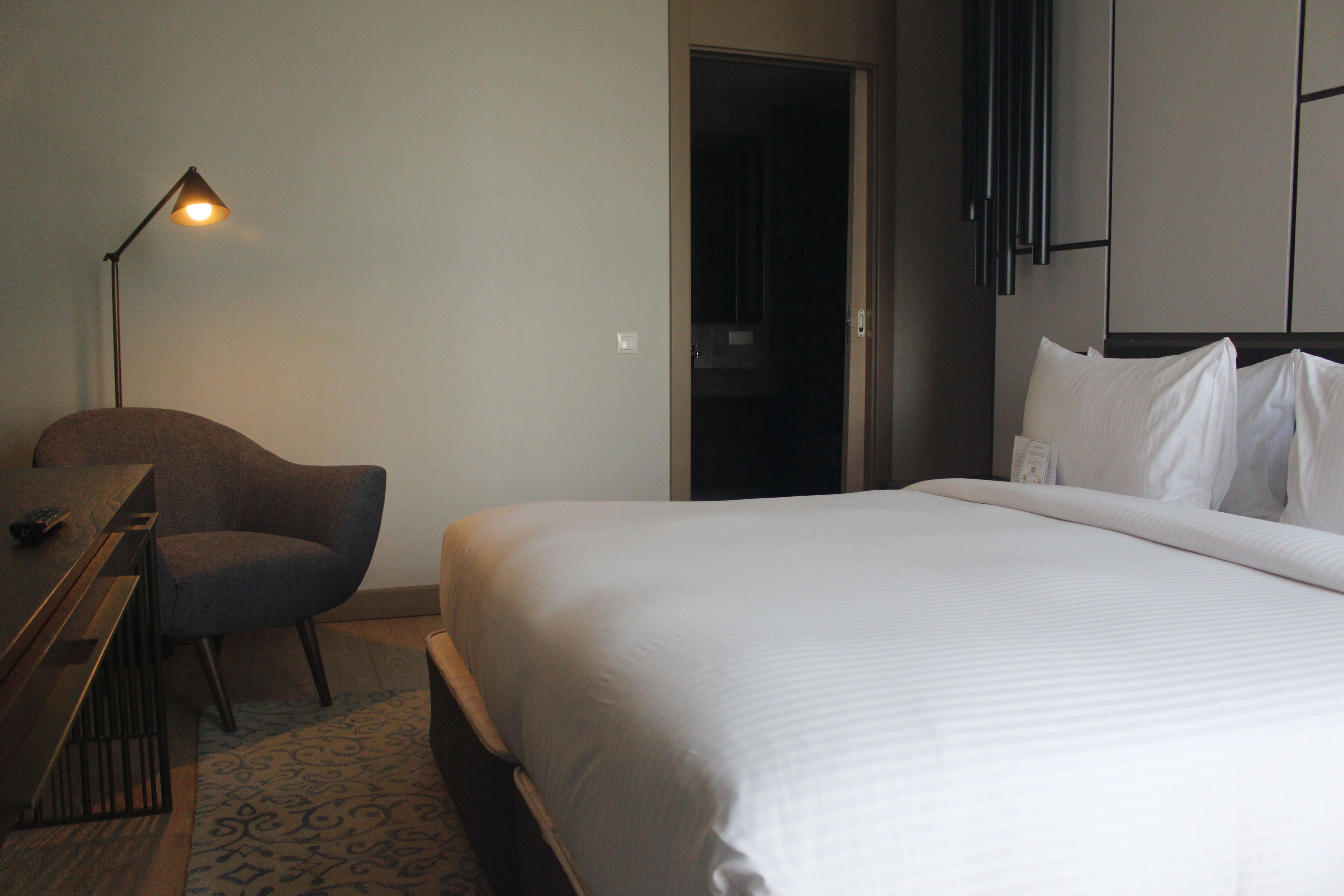 Een hotelkamer met een bed, bureau, stoel en lamp.