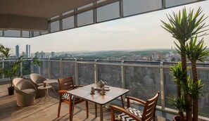 A balcony with a table and chairs, potted plants, and a city view. - Somerset Maslak Istanbul (Sariyer)