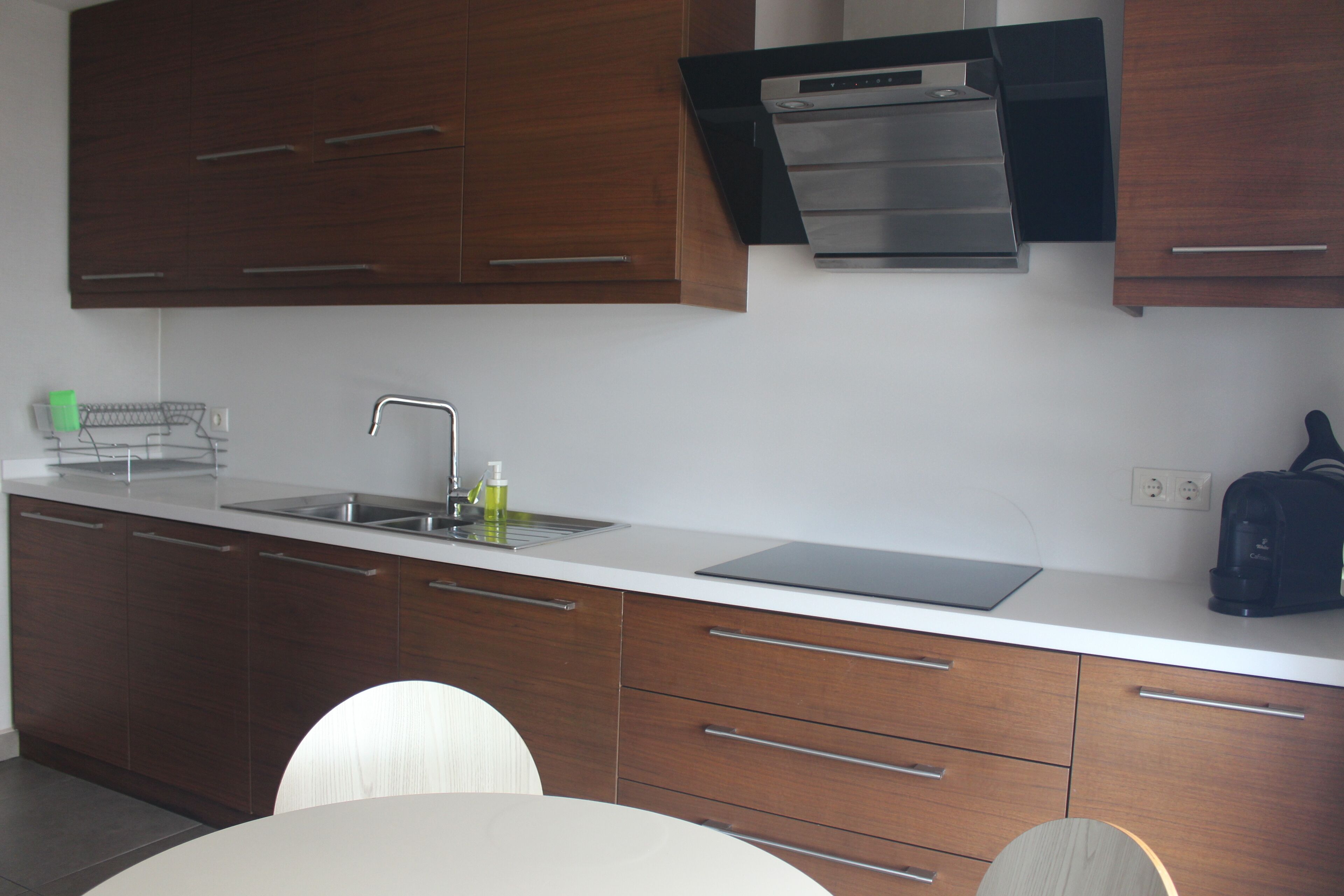 A modern kitchen with wooden cabinets, a stainless steel sink, and a black countertop.
