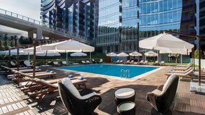 A rooftop pool area with lounge chairs, umbrellas, and a clear view of modern buildings. - Somerset Maslak Istanbul (Sariyer)