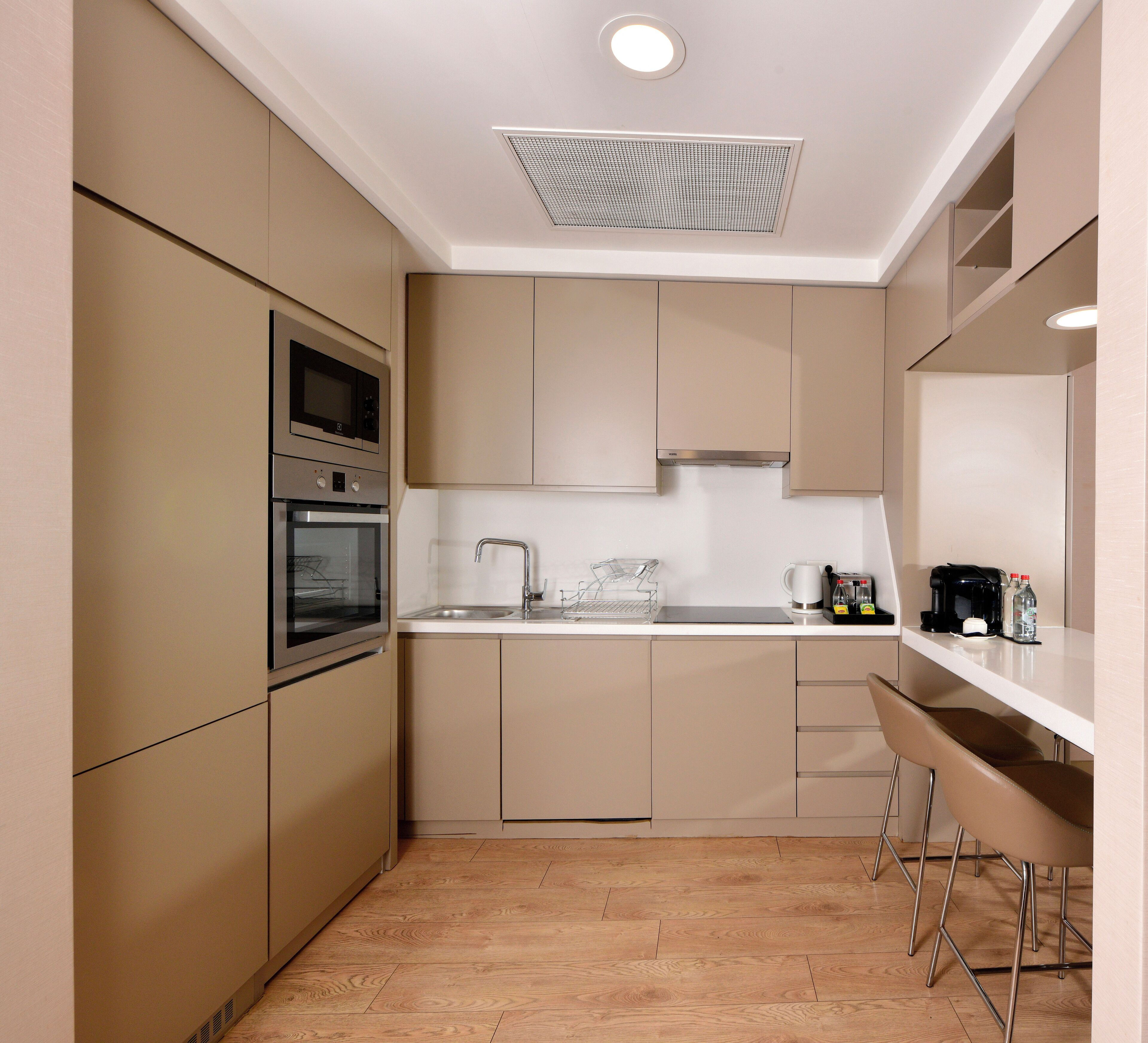 A modern kitchen with built-in appliances, a sink, and bar stools.