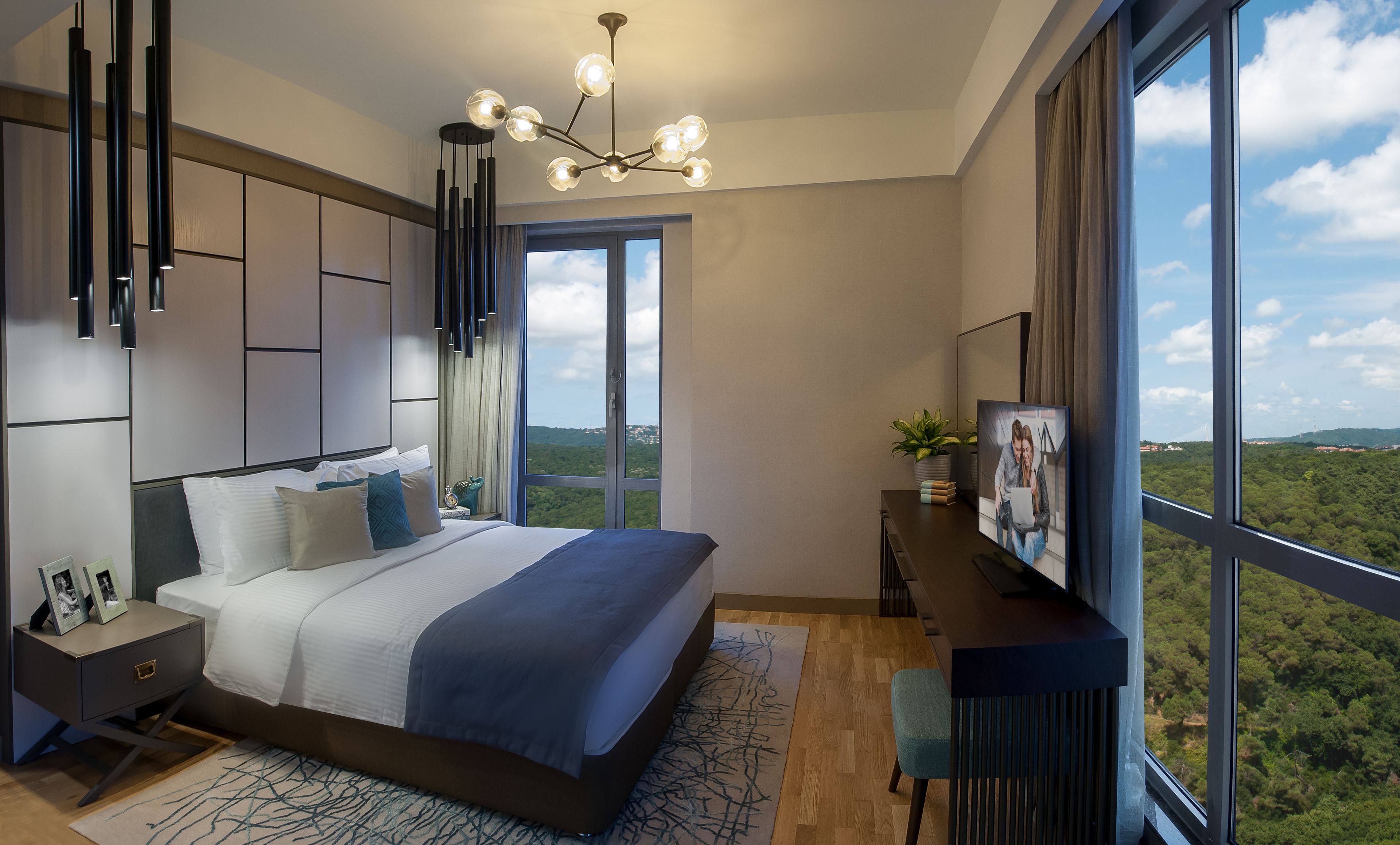 A modern bedroom with a large bed, a desk, and a view of the landscape.
