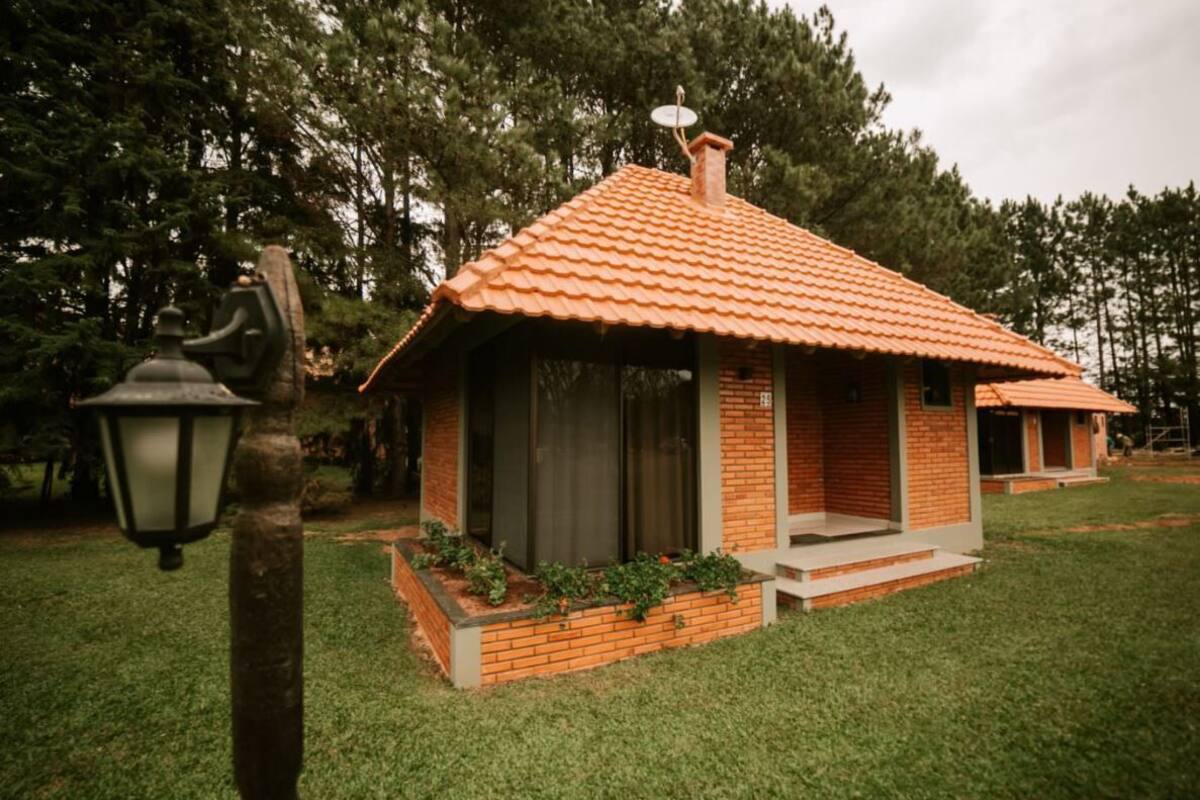 Une petite maison en briques avec un toit en tuiles, un porche et un jardin.