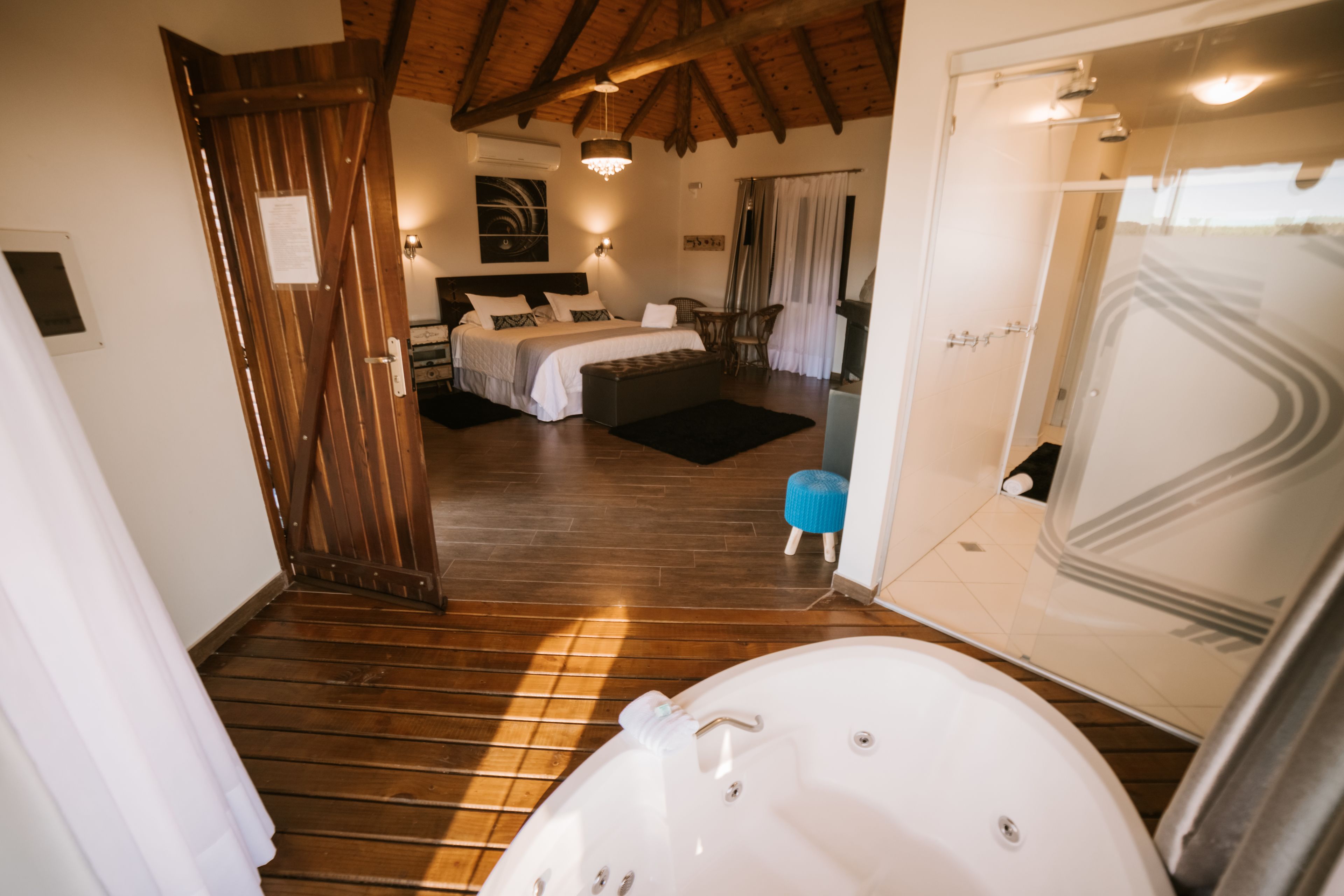 Quarto com cama grande, área de estar e banheiro com banheira.