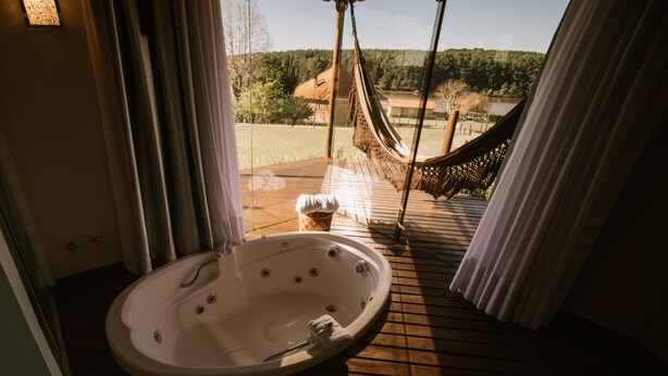 Une terrasse en bois avec un jacuzzi et un hamac.