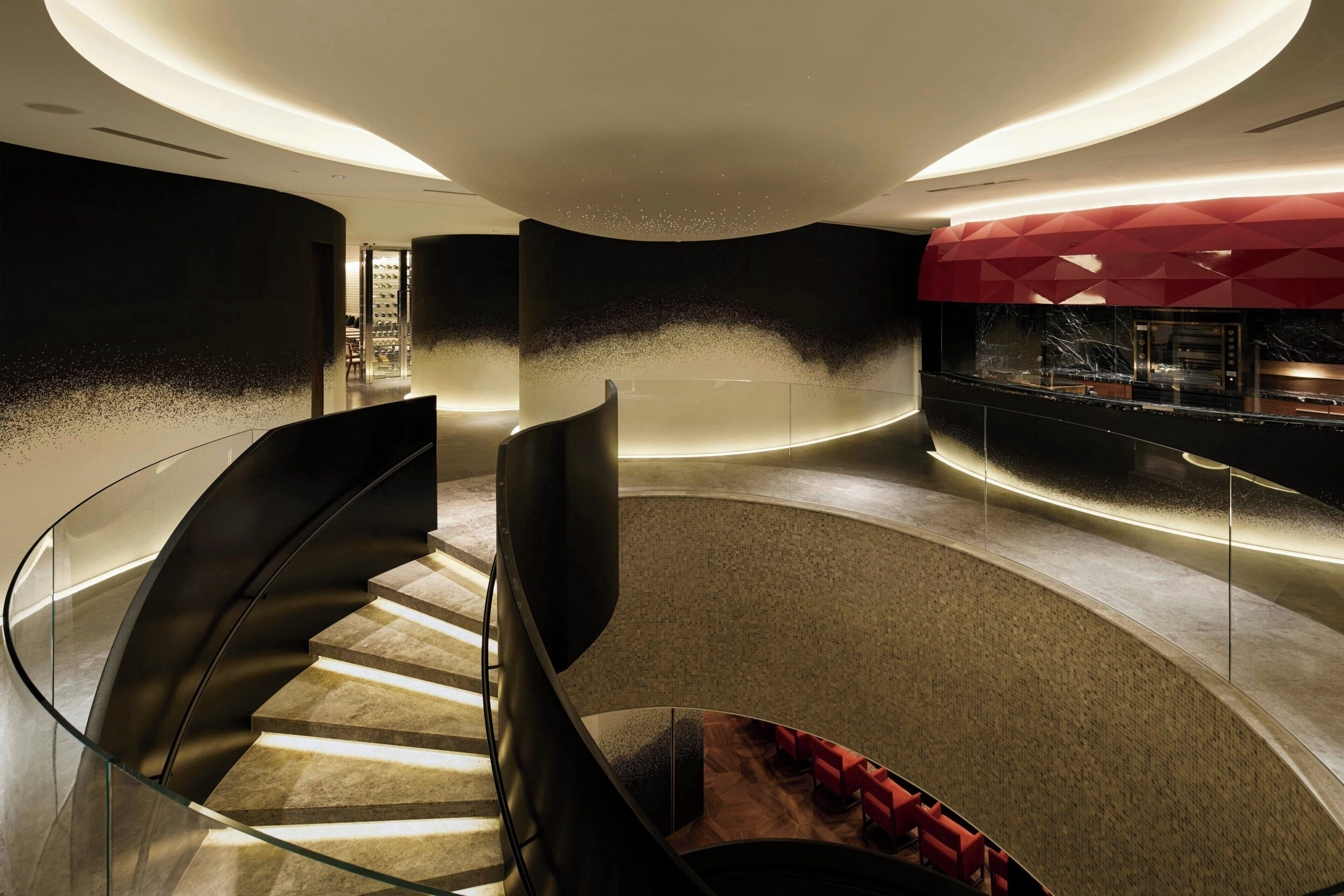 Een modern interieur met een gebogen trap, zithoek en een bar.