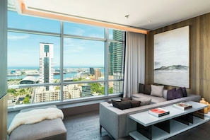 A modern living room with a large window, a grey sofa, a white pouf, and a coffee table with books. - THE AMNIS, a Luxury Collection Hotel, Kaohsiung (Kaohsiung)