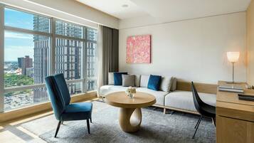 Una habitación de hotel moderna con un ventanal grande, una mesa redonda de madera, un sofá y un escritorio.