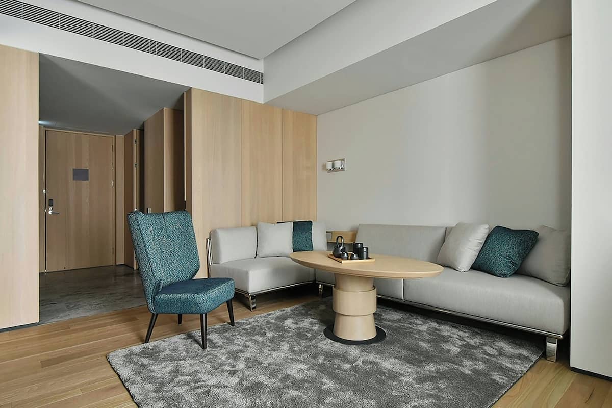 A modern living room with a sofa, a chair, a coffee table, and a door leading to another room.