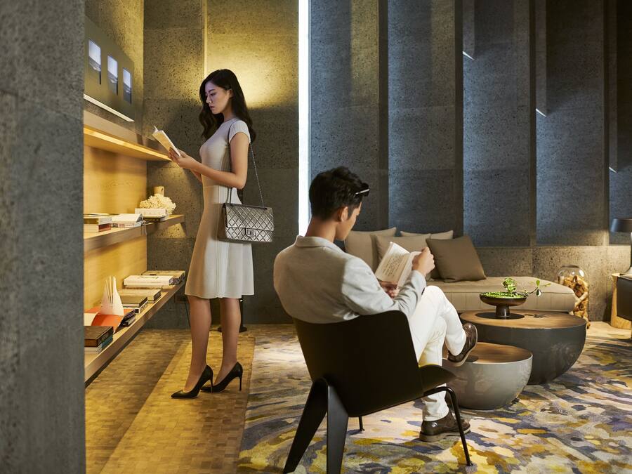 Um lobby moderno com balcão de recepção, área de estar com sofá e poltronas, e piso estampado.