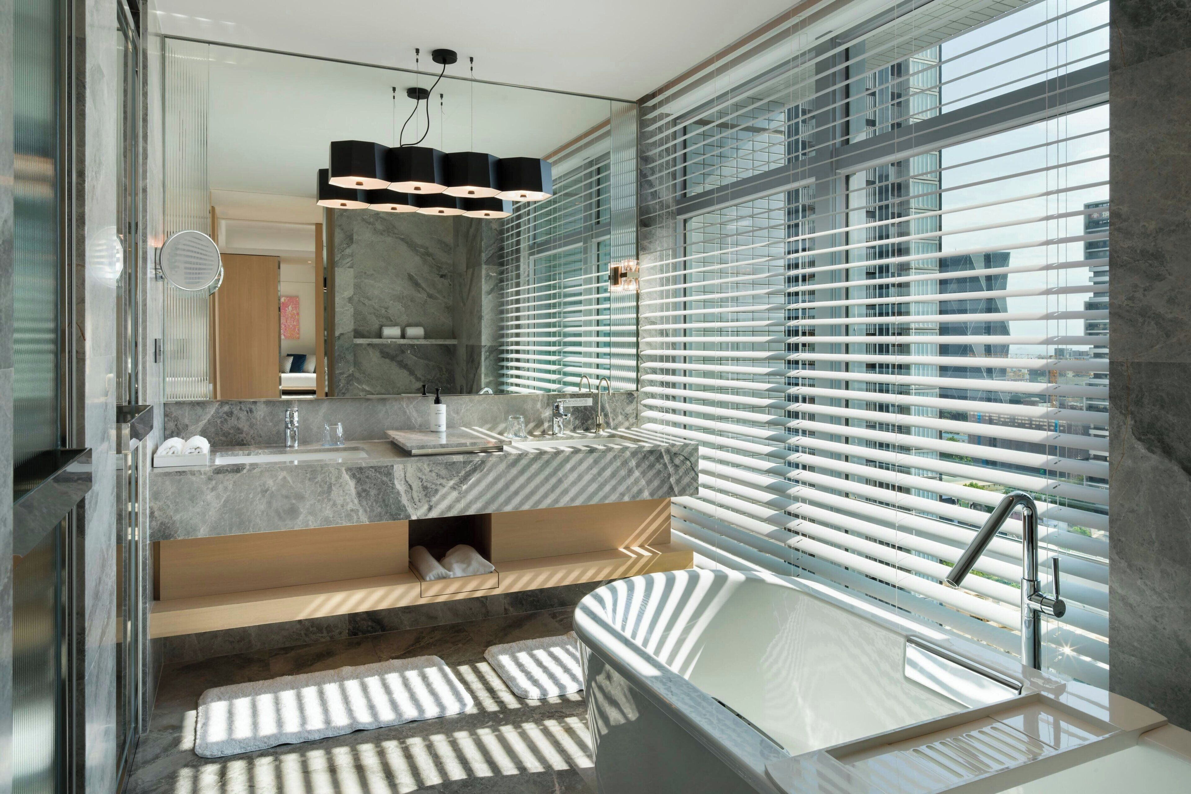 Un baño moderno con una bañera grande, dos lavamanos y un espejo amplio.