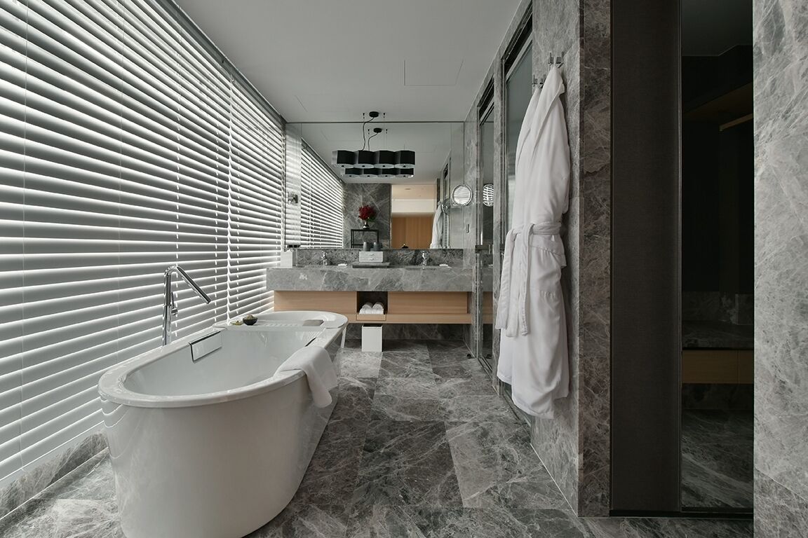 A modern bathroom with a freestanding bathtub, a large mirror, and a marble floor.