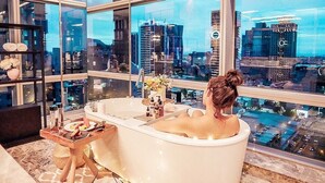 A woman relaxing in a bathtub with a city view. - THE AMNIS, a Luxury Collection Hotel, Kaohsiung (Kaohsiung)