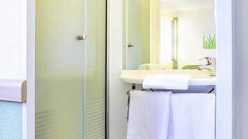 Un baño con puerta de vidrio para la ducha, un lavabo blanco, un espejo y un perchero para toallas.
