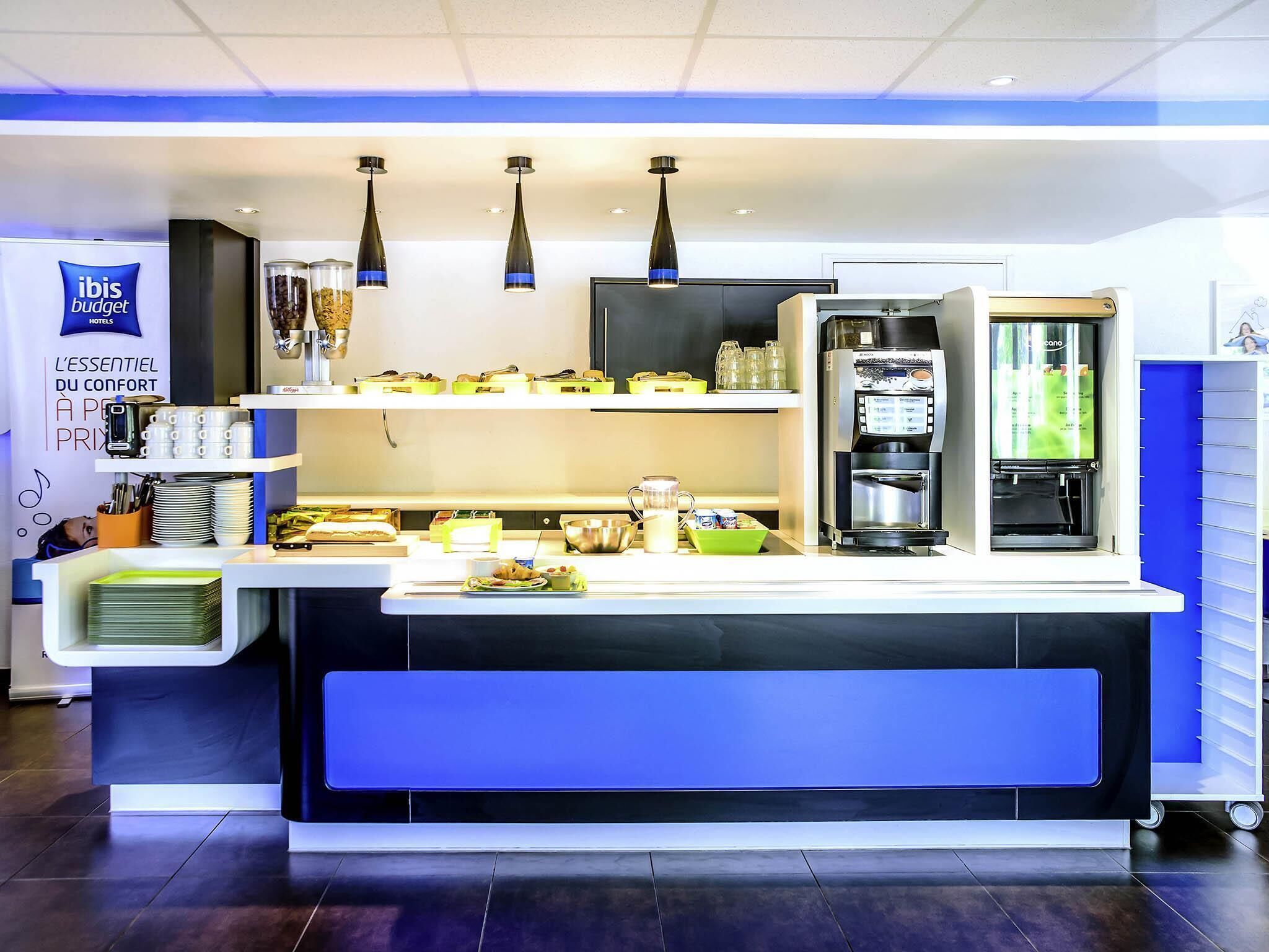 A hotel reception area with a counter, coffee machines, and a minibar.