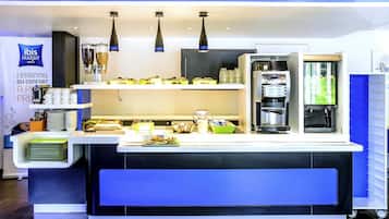 A hotel reception area with a counter, coffee machines, and a minibar.