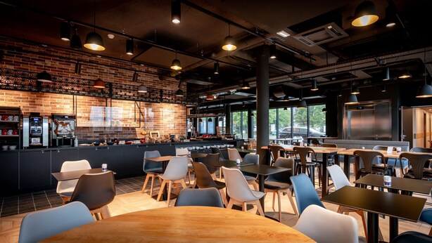Una cafetería moderna con paredes de ladrillo, una barra y amplio espacio para sentarse.