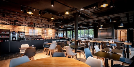 A modern cafe with brick walls, a bar area, and ample seating.