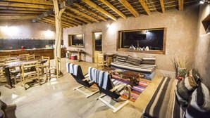 Un int érieur rustique avec des poutres en bois, un coin repas, un canapé et une grande fenêtre.