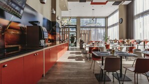 Un restaurante moderno con una barra larga, armarios rojos y diversas opciones de asientos.