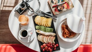 A white tray with a camera, a notebook, a cup of coffee, a plate of sliced fruits, and a teapot. - ibis Mohammedia (Mohammedia)