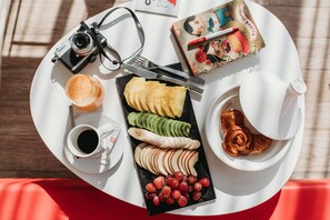 A white tray with a camera, a notebook, a cup of coffee, a plate of sliced fruits, and a teapot. - ibis Mohammedia (Mohammedia)