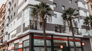 A multi-story hotel with a modern design, featuring balconies and palm trees. - ibis Mohammedia (Mohammedia)