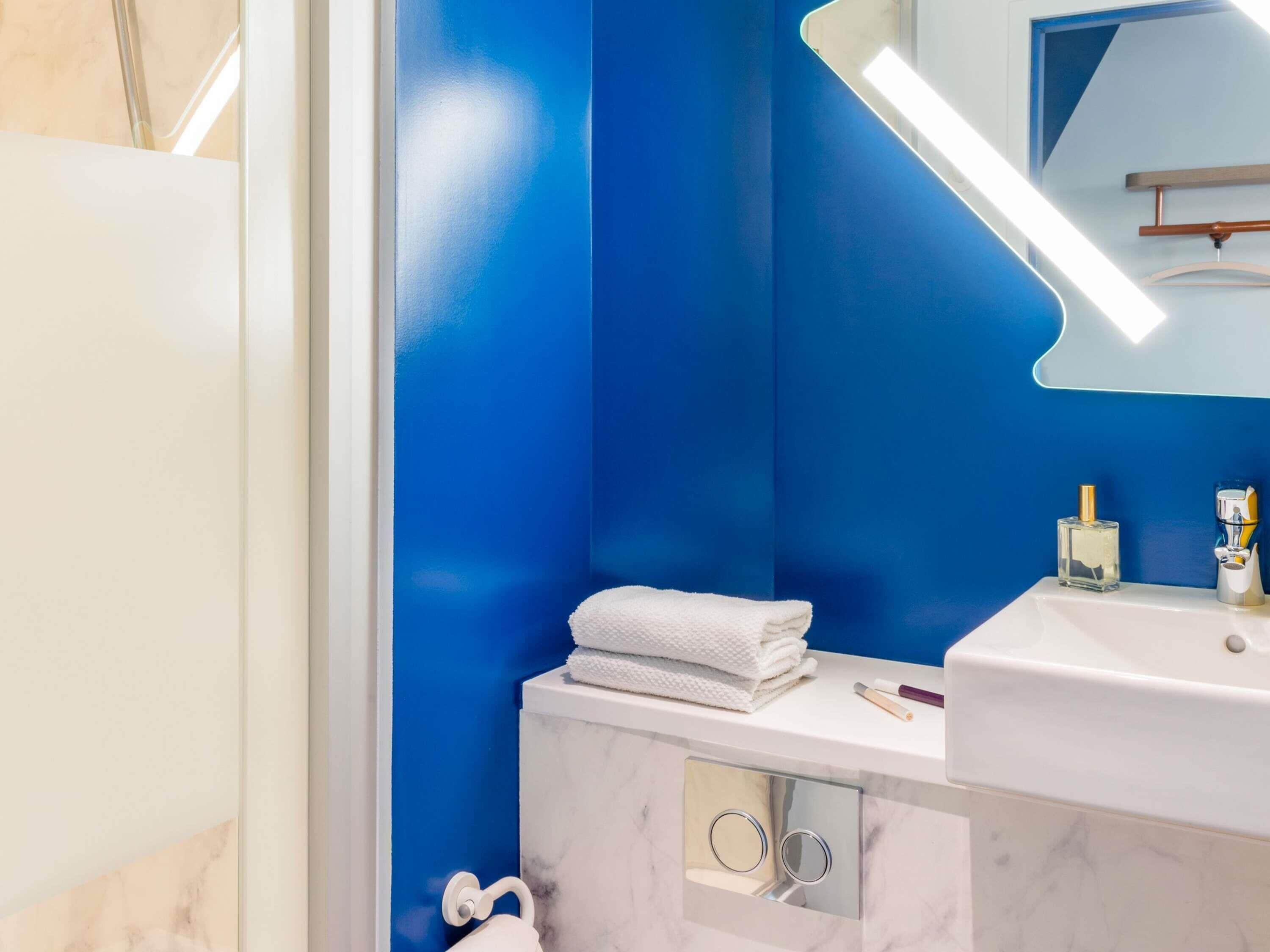 A bathroom with a blue wall, a white sink, and a mirror.