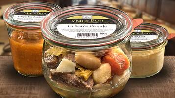 Three glass jars with metal lids, containing different food items, placed on a wooden surface.
