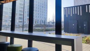 Um edifício moderno com grandes janelas, uma área de estar com bancos altos e vista para um arranha-céu.