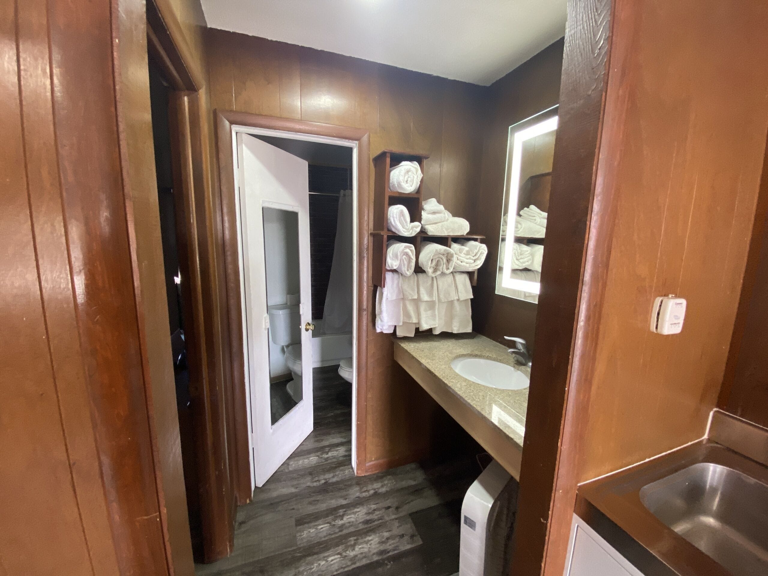 Un baño con detalles de madera, un lavamanos, un espejo y un perchero para toallas.
