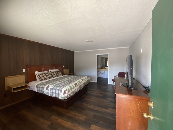 A bedroom with a wooden bed, a dresser, and a television. - Rainbow Lodge (South Fork)